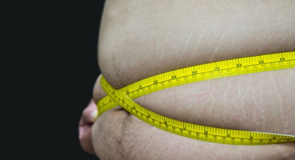 Tlustý asijské muž s měřicí páska boční pohled izolované na černém - Fotografie, Obrázek
