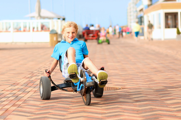 Happy boy riding pedal car on the beach - Fotó, kép