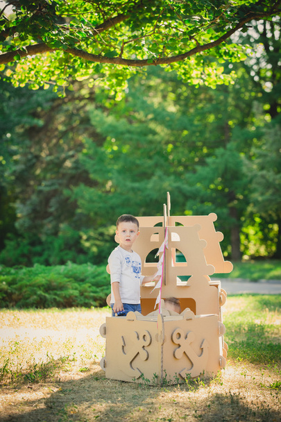 Boy and girl playing in a cardboard boat - Фото, зображення