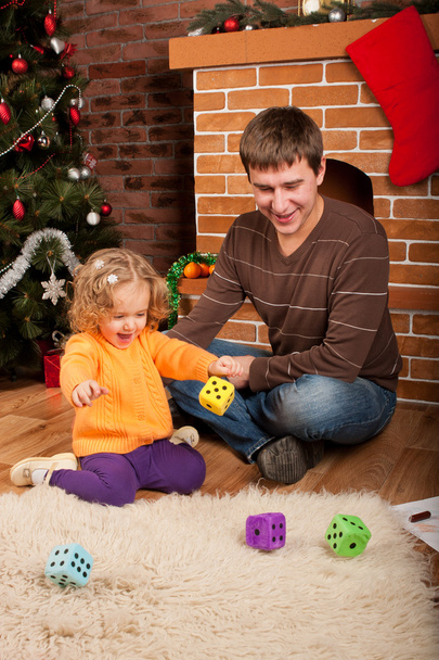Little girl play with dad near Christmas tree - Foto, afbeelding
