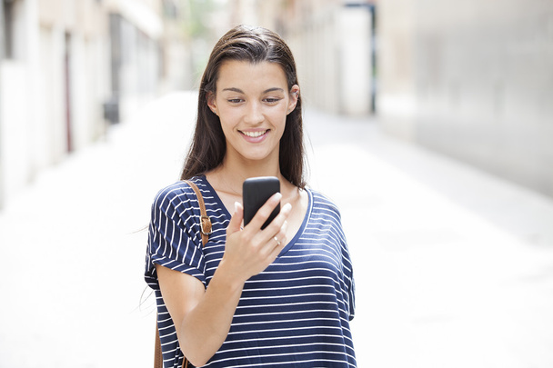 A portrait of a smiling beautiful woman texting with her phone - Foto, Imagen