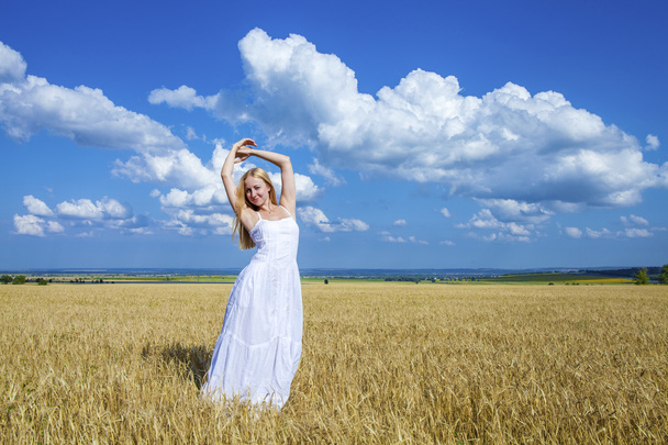 Young beautiful woman in a long white dress is standing in a whe - Фото, зображення