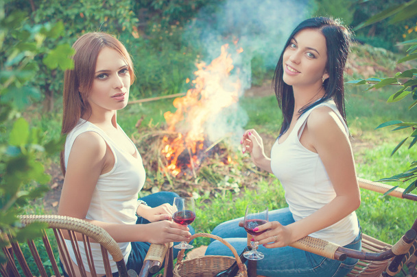 girls with red wine glasses near bonfire - Photo, Image
