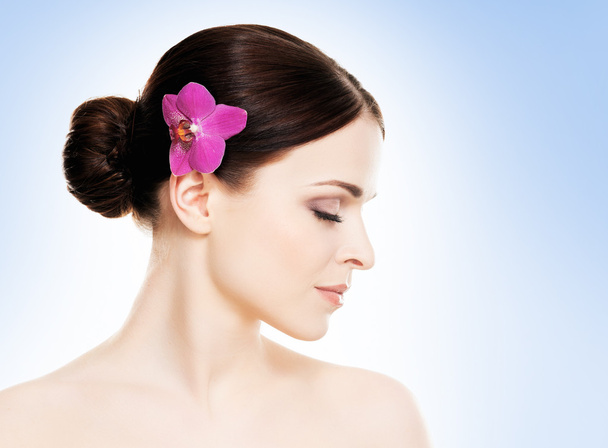 Healthy woman with orchid flower in hair - Фото, изображение