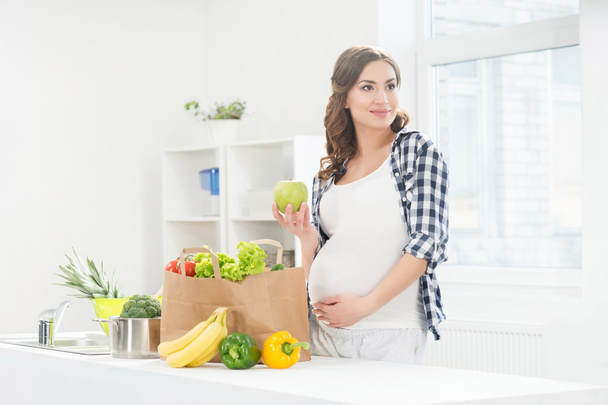 pregnant woman in kitchen - Foto, afbeelding