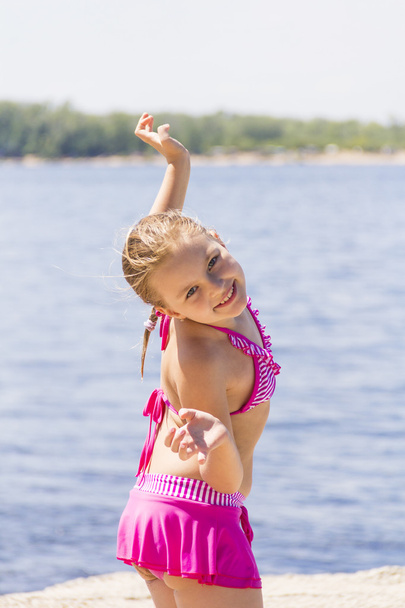 Cute girl on the riverbank in pink swimsuit - Fotografie, Obrázek