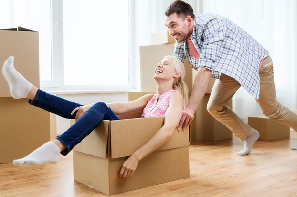 couple with cardboard boxes having fun at new home - Фото, изображение