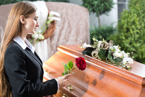 rouwende vrouw bij begrafenis met doodskist - Foto, afbeelding