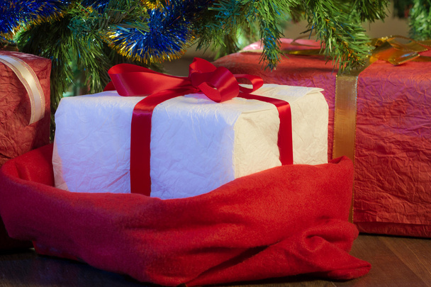Closeup red gift and green christmas tree - Фото, изображение
