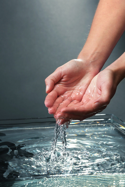 Female hands with water splashing on dark background - Foto, Imagem