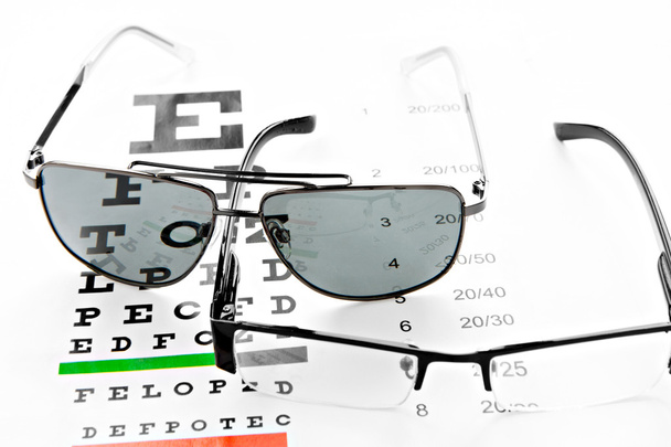 szemüveget és napszemüveget látás chart-on fehér háttér - Fotó, kép