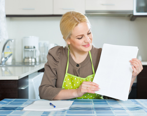 Mulher com documentos na cozinha
 - Foto, Imagem