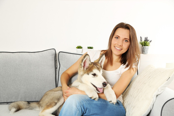 Woman with her malamute dog on sofa  - Foto, afbeelding