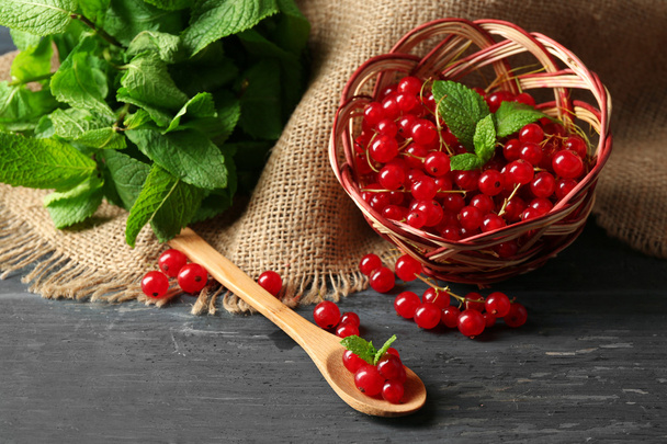 Ripe red currant in wicker basket on wooden background - Foto, immagini