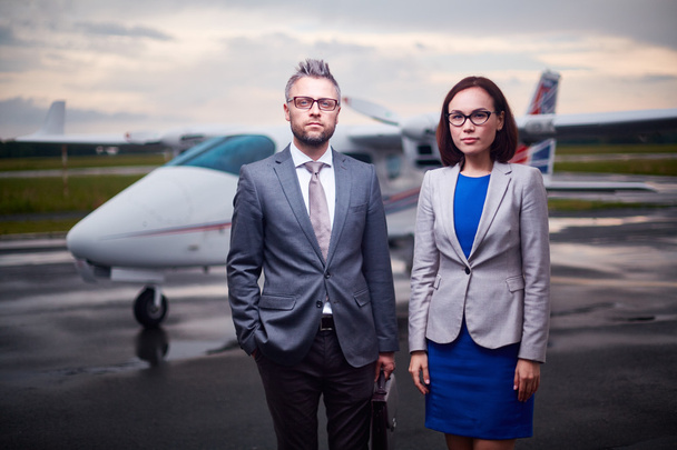serious colleagues with airplane on background - Photo, Image