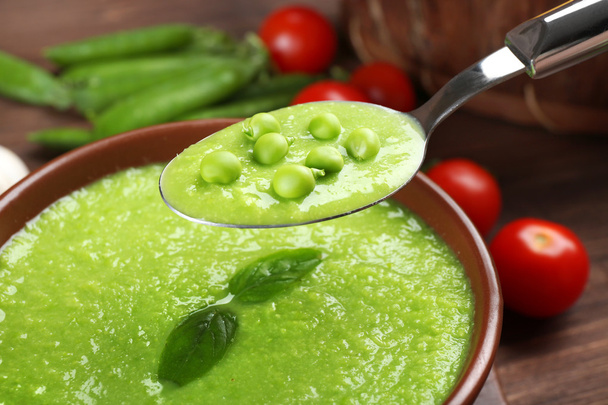 Tasty peas soup and cherry tomatoes on table close up - Foto, afbeelding