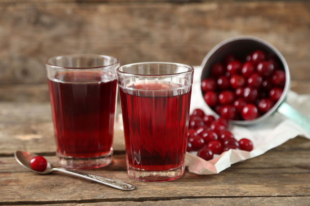 Two glasses with cherry juice on table, on wooden background - Foto, imagen