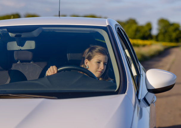 Женщина-водитель проверяет боковое зеркало
 - Фото, изображение