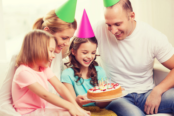 Famille souriante avec deux enfants en chapeaux avec gâteau
 - Photo, image