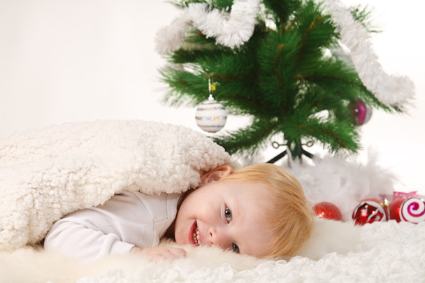Santa boy lies near the Christmas tree - Фото, зображення