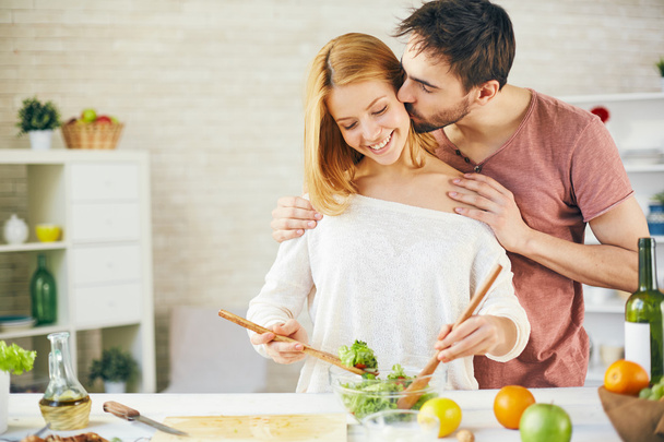 чоловік цілує свою дружину на кухні
 - Фото, зображення