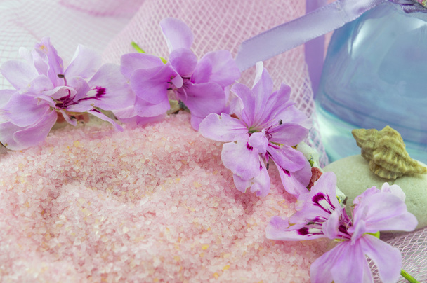 Flor rosa arredondando sal de banho rosa com óleo etérico em uma garrafa
 - Foto, Imagem