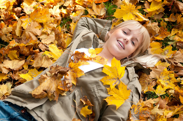 νεαρή γυναίκα που βρίσκεται σε Φθινοπωρινά φύλλα - Φωτογραφία, εικόνα