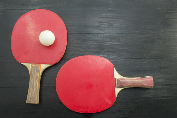 zwei rote Tischtennisschläger auf dunklem Hintergrund - Foto, Bild