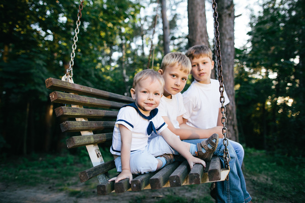 three brothers sitting on swing - Fotoğraf, Görsel