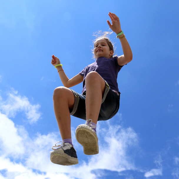 little girl makes a big jump and blue sky in summer - Photo, Image