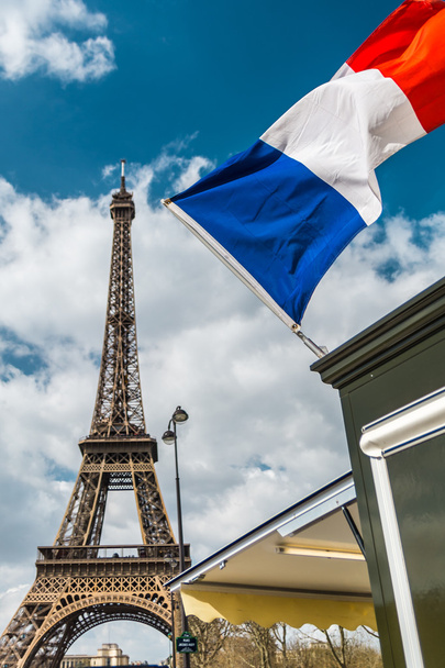 Bandera de Francia sobre cielo azul nublado y torre Eiffel en París
 - Foto, Imagen