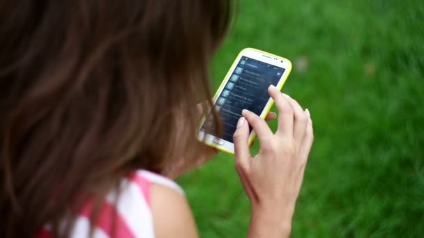 Hermosa mujer joven escribiendo sms en el teléfono inteligente
 - Metraje, vídeo