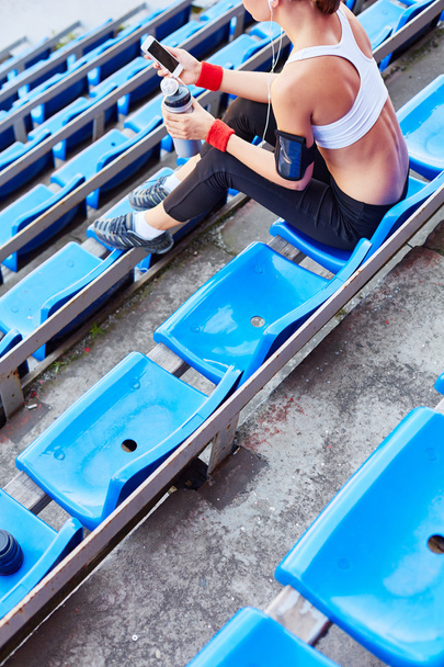 kobieta w activewear siedzi na stadionie - Zdjęcie, obraz