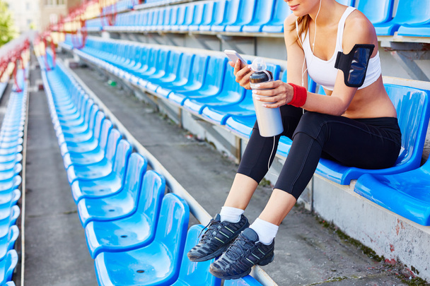 mulher com smartphone sentado no estádio
 - Foto, Imagem