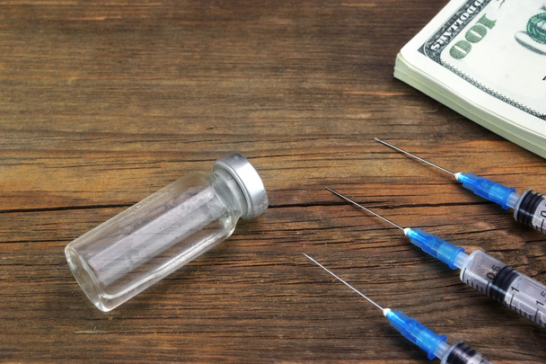 medizinische Spritzen, Fläschchen und Wattestäbchen mit Dollarscheinen in Großaufnahme - Foto, Bild