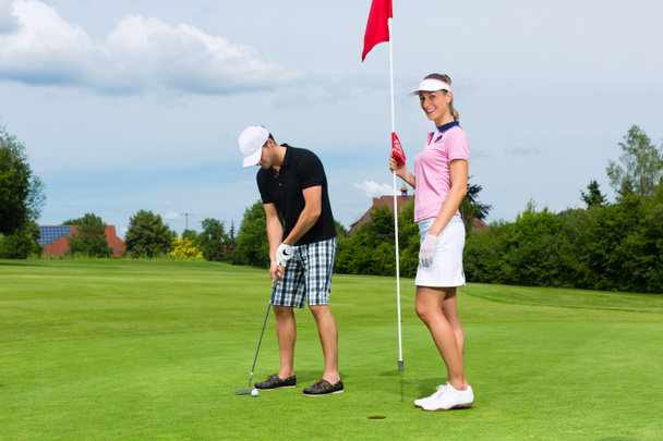 Nuori urheilullinen pari pelaa golfia kentällä
 - Valokuva, kuva