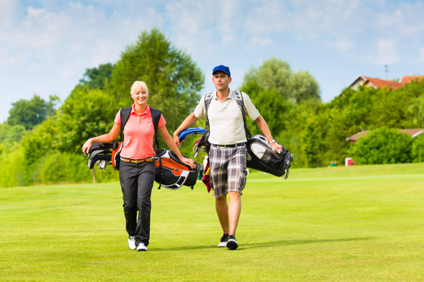 Jovem casal esportivo jogando golfe em um campo
 - Foto, Imagem