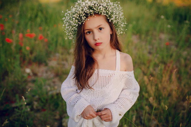 hermosa niña posando en falda una corona de amapolas
 - Foto, imagen