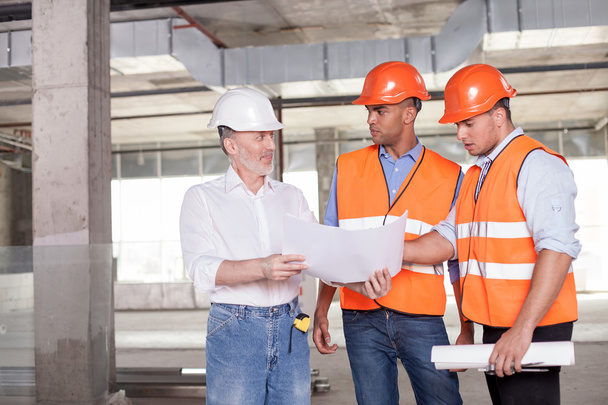 Cheerful builders are discussing a plan of construction - 写真・画像