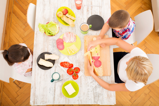 Happy family having breakfast at home - Фото, изображение