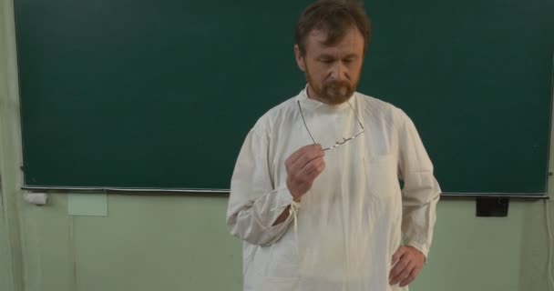 Professor, man, scheikundige, bioloog close-up in White Medical robe houdt de klas op de tribune, nam de bril af en droeg weer - Video