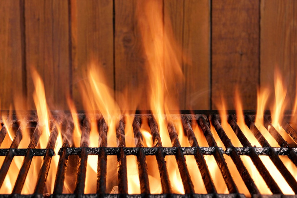 Parrilla de hierro fundido de carbón de barbacoa en llamas y fondo de madera
 - Foto, Imagen