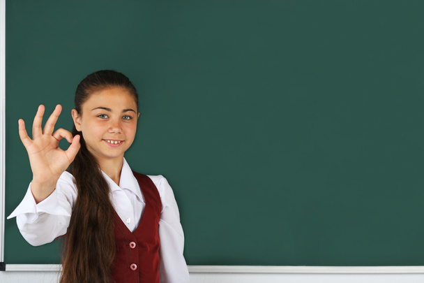 little girl standing near blackboard - Foto, afbeelding