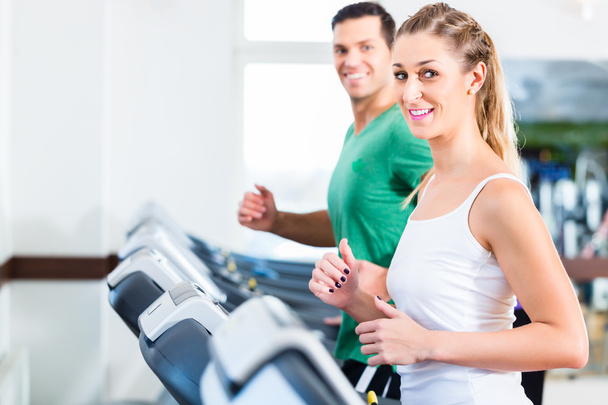 Homme et femme sur entraîneur elliptique dans la salle de gym
 - Photo, image