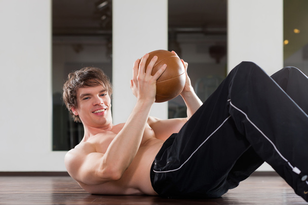 Mann trainiert mit Medizinball in Turnhalle - Foto, Bild