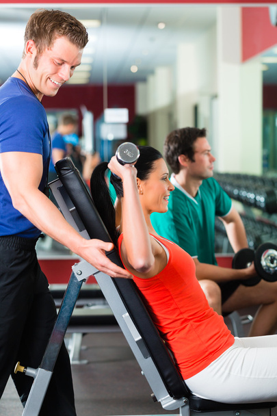 Woman and Personal Trainer in gym with dumbbells - Photo, Image