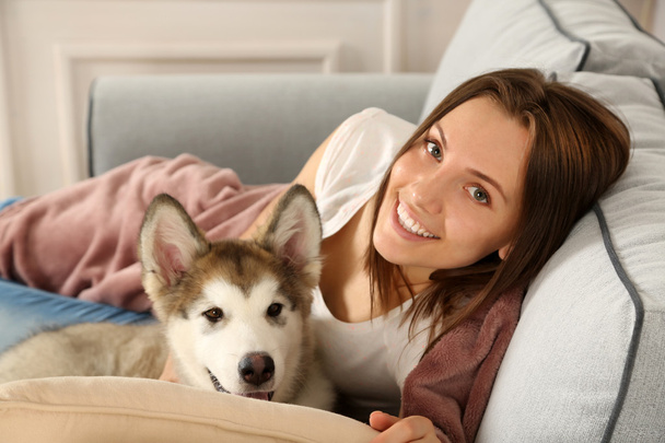Woman lying with malamute dog on sofa - Foto, immagini