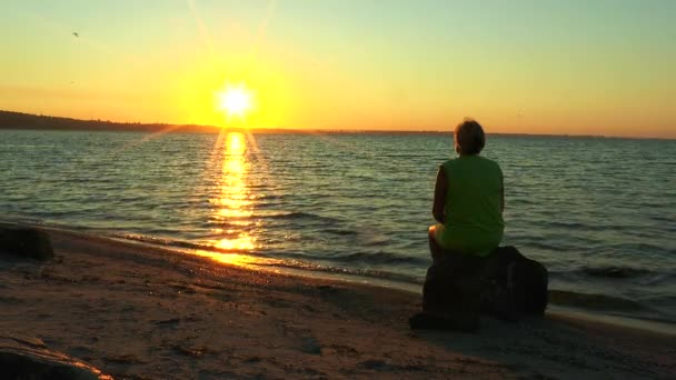 Žena při pohledu na východ slunce nad mořem - Záběry, video