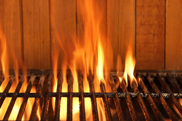 Flaming BBQ Charcoal Cast Iron Grill And Wood Background - Fotó, kép
