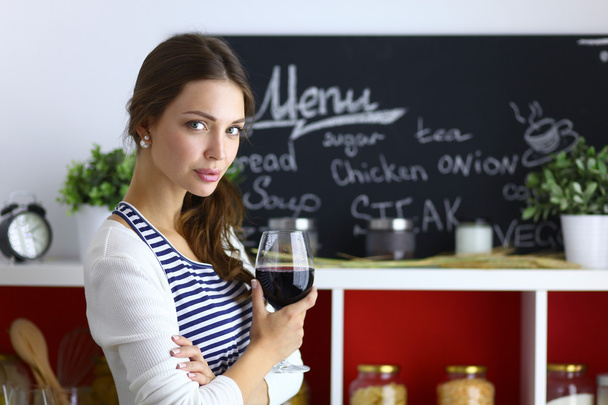 Pretty woman drinking some wine at home in kitchen - Foto, Bild